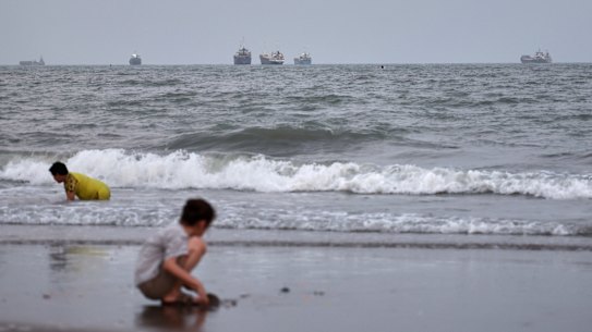 La scorsa settimana, alcuni bambini giocavano su una spiaggia mentre navi mercantili erano ancorate nello Stretto di Ormuz al largo di Bandar Abbas, in Iran.