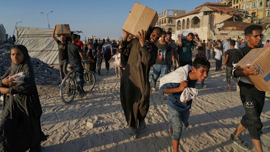 Palestinians carry sacks and boxes of food and humanitarian aid unloaded from a World Food Program convoy that had been heading to Gaza City, in the northern Gaza Strip, Monday, June 16, 2025. (AP Photo/Jehad Alshrafi)