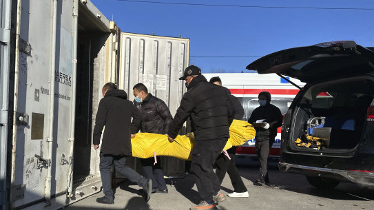 Workers transfer a body into a container for storage at a crematorium in Beijing last weekend.