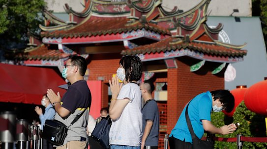 People wear face masks to protect against the spread of the coronavirus and pray outside Hsing Tian Kong Temple in Taipei, Taiwan.