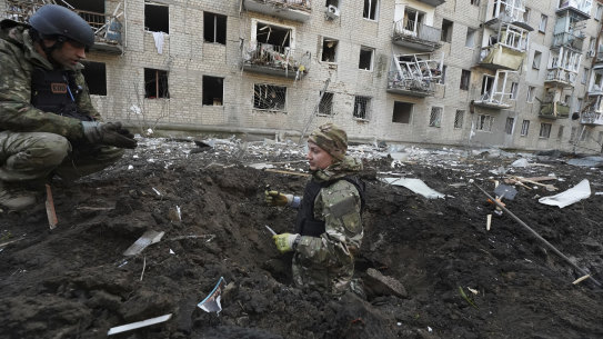 Police officers inspect a crater in front of a damaged residential building hit by a Russian strike in Kharkiv, Ukraine, on Wednesday. 