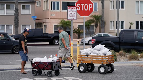 Long Beach residents pull wagons with sandbags.
