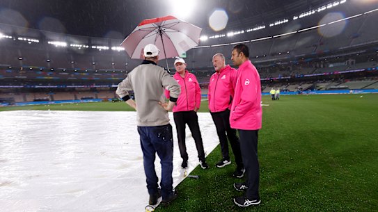 MCG curator Matt Page confers with umpires at the MCG on Friday night.