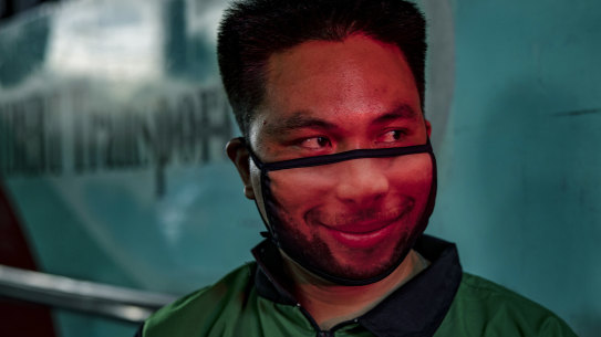 A worker wearing a novelty face mask is illuminated by a traffic light in Manila on Monday, the first day of relaxed quarantine measures.