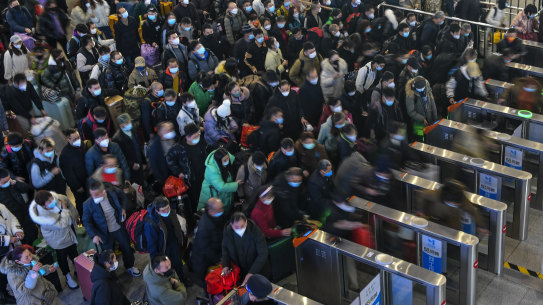People wearing face masks with their luggage line up to enter the ticket counters to catch their trains at the railway station in Suzhou in east China’s Jiangsu Province on Saturday.