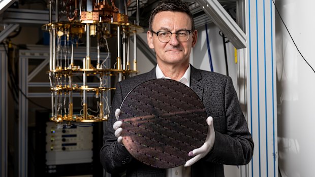 Diraq chief executive Andrew Dzurak, holding a silicon wafer in front of a cryogenic fridge. The company plans to sell a quantum computer by 2029.