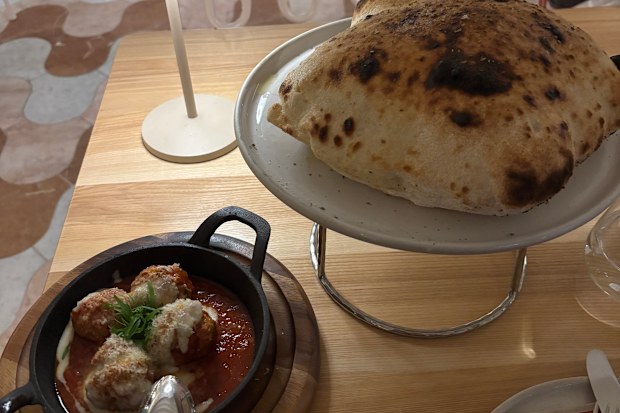 A restaurant table with a plate of meatballs and bread
