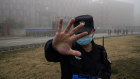 A guard stands in front of the Wuhan Institute of Virology, urging journalists not to take photos.