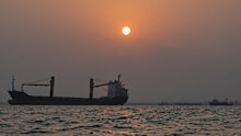 The sun sets over commercial vessels anchored in the Strait of Hormuz off Bandar Abbas, Iran.