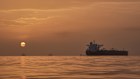 The sun rises behind tankers anchored in the Strait of Hormuz.
