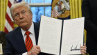 Trump holds up the executive order outlining the steel and aluminium tariffs.