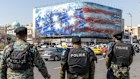 Anti riot police stand in front of a giant anti-US billboard depicting the destruction of a US aircraft carrier, in downtown Tehran. 