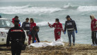 Italian Red Cross volunteers and coast guards recover a body after a boat broke apart in rough seas.