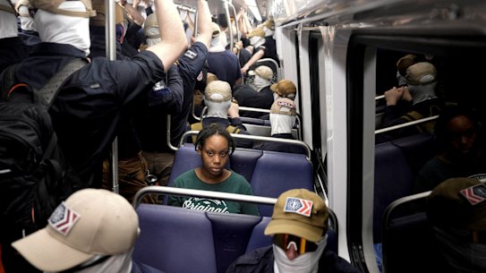 A commuter sits as masked members of the white supremacist Patriot Front ride the Washington subway on July 4.