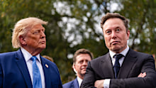 President Donald Trump listens as Elon Musk speaks outside the West Wing of the White House.