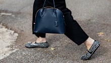 A guest wears white jacket, black skirt, Alaia shoes, navy bag outside Ferragamo during the Milan Fashion Week Menswear Spring/Summer 2025 on September 21, 2024 in Milan, Italy.