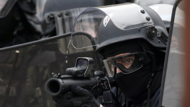 A police officer aims a flash ball gun during clashes with yellow vest protesters on the famed Champs Elysees avenue in Paris on Saturday.