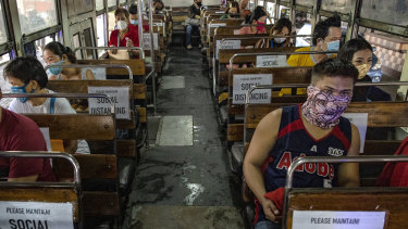 Commuters sit on a bus with seats spaced to observe social distancing in Manila.