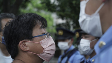 Anti-Olympic protestors are blocked by police officers in front of the National Stadium where the closing ceremony of the Tokyo Olympics is set to start.