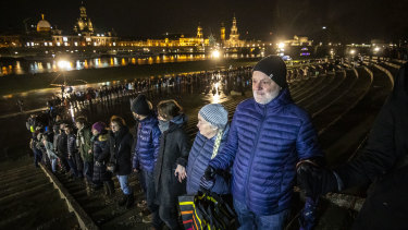 People standing along the Elbe River across from the historic Dresden city centre link hands to create a human chain in commemoration of the 75th anniversary of the Allied firebombing of Dresden.