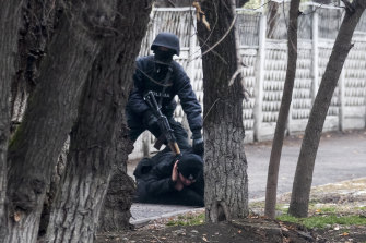 An armed riot police officer detains a protester in Almaty, Kazakhstan, on Saturday.
