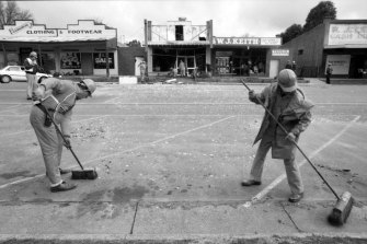 State Emergency Service workers sweep up debris in High Street, Wedderburn, after the early morning bombing of a fish shop.