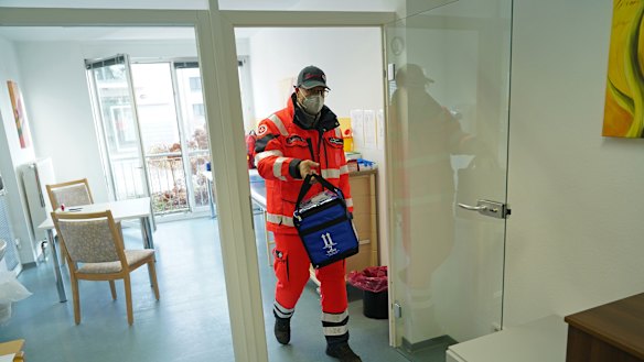 A German Red Cross worker carries a thermo container to pick up the Pfizer-BioNTech COVID-19 vaccine at a nursing home in Grossraeschen.
