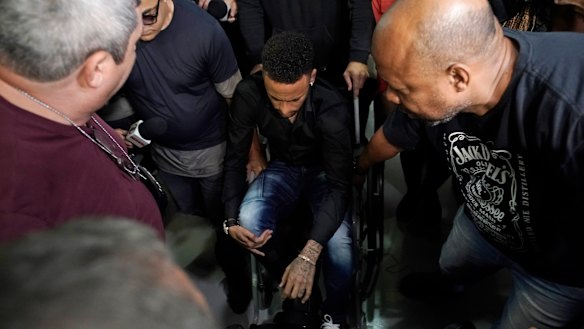 Brazilian soccer player Neymar arrives to a police station, in a wheelchair due to an ankle injury, in Rio de Janeiro, on THursday. Polcie say he will testify soon.