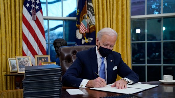 President Joe Biden signs his first executive orders in the Oval Office of the White House.