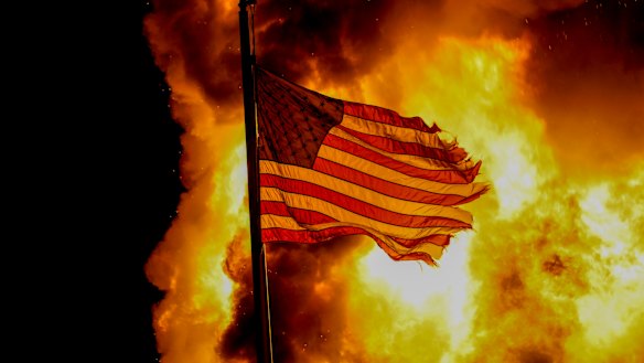 A flag flies over a department of corrections building ablaze during protests in Kenosha, Wisconsin. 