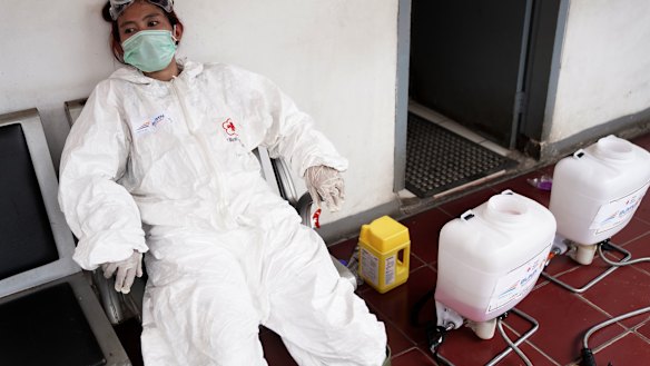 A member of the Indonesian Red Cross Society takes a break after spraying disinfectant at the Kemayoran train station in Jakarta.