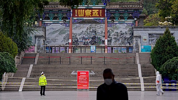 A worker stands at the entrance to Wuquan Mountain which is closed to prevent visitors gathering in Lanzhou city in Gasu province, north-west China, on Monday.