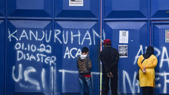People peer inside a gate at Kanjuruhan Stadium, the site of this month’s deadly stampede. The venue will be demolished and rebuilt, Indonesia President Joko Widodo has announced.