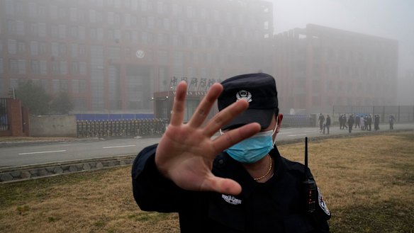 A security guard moves journalists away from the Wuhan Institute of Virology as the WHO team arrives for a field visit in February.
