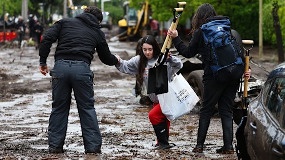 People walk the mud-flooded streets of the Las Condes district a day after heavy rains hit Chile’s capital.
