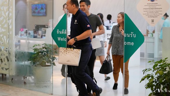 A staff member, left, from the British embassy arrives at Samitivej Hospital in Bangkok, Thailand.