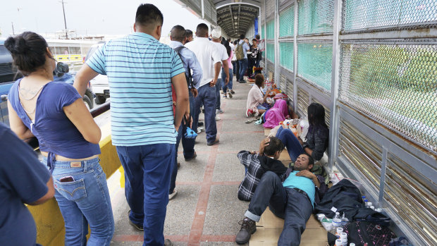 Migrant families rest from their travels to Matamoros, Mexico, along Gateway International Bridge which connects to Brownsville, Texas, as they seek asylum in the United States.