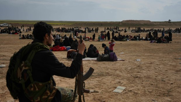 A member of the US-backed Syrian Democratic Forces (SDF) watches over people who were evacuated out of the last territory held by IS militants on Tuesday, local time. 