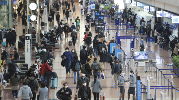 People wear face masks at Haneda Airport in Tokyo. Four passengers from Brazil quarantined at the airport have been diagnosed with carrying a new variant of coronavirus.