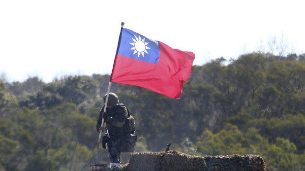 A soldier holds a Taiwanese flag during a military exercise aimed at repelling an attack from China in Hsinchu County, northern Taiwan. 