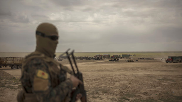 A member of the Syrian Democratic Forces (SDF) stands guard at a reception area for people evacuated from the last shred of territory held by Islamic State militants, outside Baghouz.