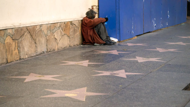 A person sits near stars on the Hollywood Walk of Fame in Los Angeles. California experienced the sharpest rise of homelessness of any state last year.