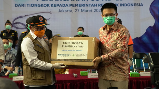 Chinese and Indonesian officials pose with aid supplied by China as it arrives in Jakarta.