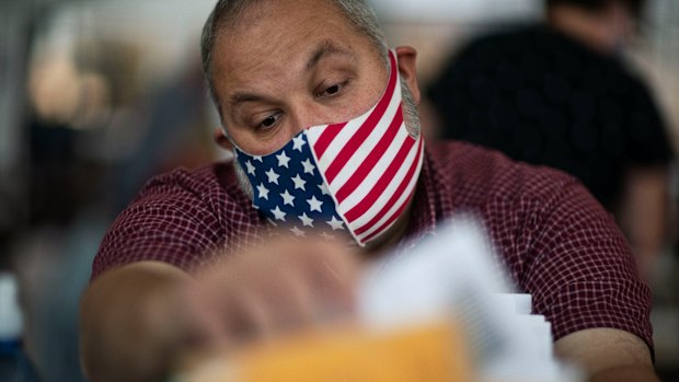 Election inspector Ron Takala processes ballots as the counting of absentee votes begins at City Hall in Warren, Michigan.