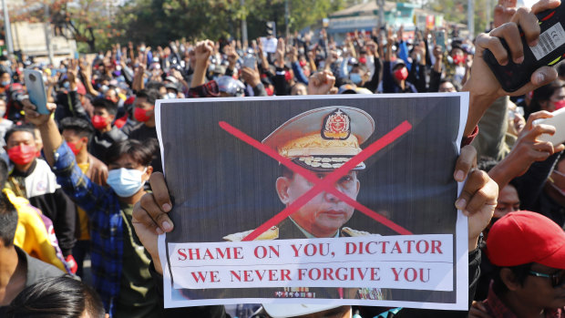 A protester holds a placard with a defaced image of Myanmar military Commander-in-Chief Senior General Min Aung Hlaing.