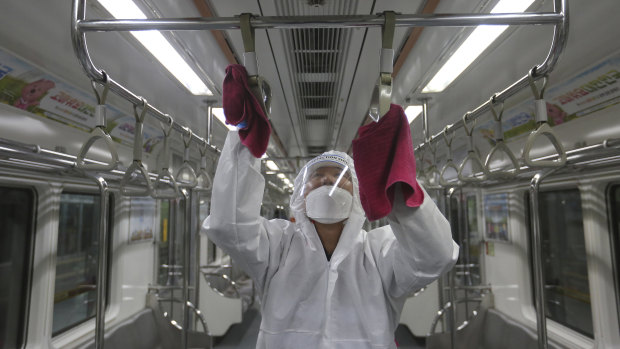 An employee disinfects handles on a subway train in Seoul.