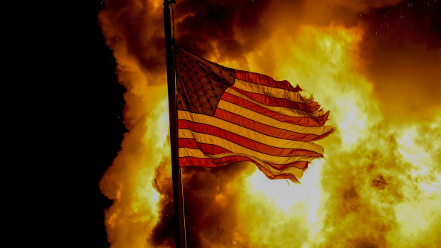 A flag flies over a department of corrections building ablaze during protests in Kenosha, Wisconsin. 