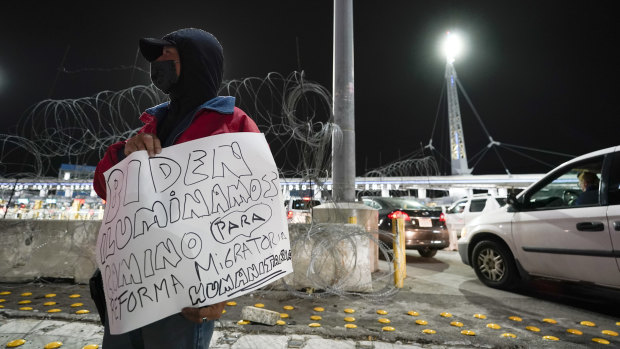 A man holds a sign during a vigil in support of migrants as he stands at the entrance to the San Ysidro port of entry along the US-Mexico border in Tijuana.