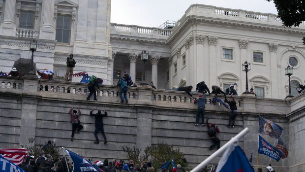 Supporters of President Donald Trump climb the West wall of the the US Capitol.
