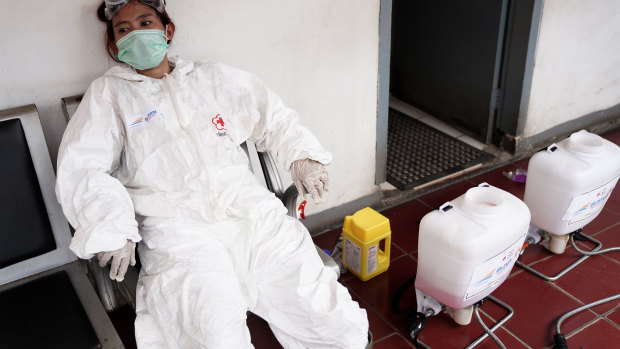 A member of the Indonesian Red Cross Society takes a break after spraying disinfectant at the Kemayoran train station in Jakarta.